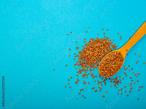 Buckwheat in a wooden spoon on a blue background, on the right side.