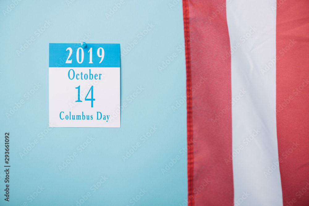 Fototapeta premium paper calendar with Columbus Day inscription near part of American national flag on blue background