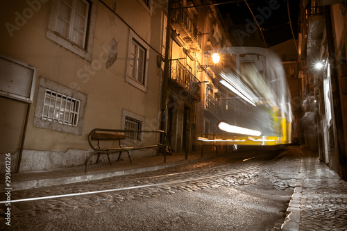 Famous yellow tram 28 in motion blur at night in Lisbon. long exposure of tram in old part of city