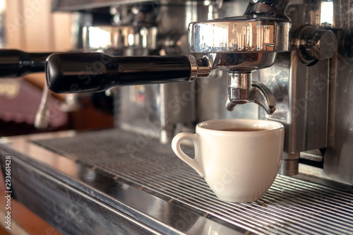 Cup of coffee under the nozzle of a coffee machine