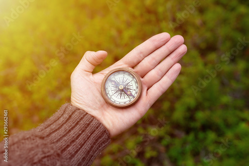 Hiker man searching direction with a compass in the forest. View of hand. 