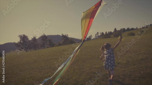 Retro look. Slow motion of a little girl flying a kite. photo