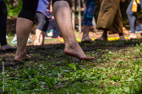 Diverse people enjoy spiritual gathering A ground level perspective on an intergenerational group of people, standing barefooted on grass and soil as they celebrate native cultural dance in nature.
