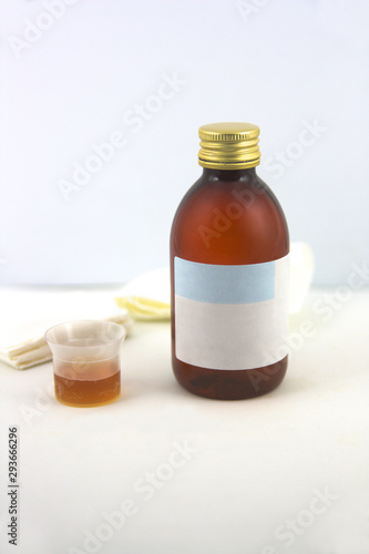 Syrup next to a medicine measure and some scarves