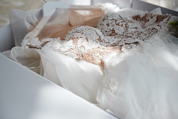 Beautiful luxury wedding dress in white box on bed, copy space. Bridal morning preparations. Wedding concept