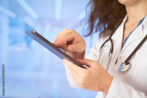 Woman doctor using tablet computer while standing straight in hospital