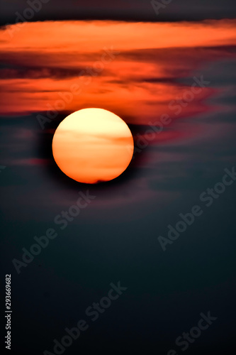 yellow-orange sun with red clouds on a black sky