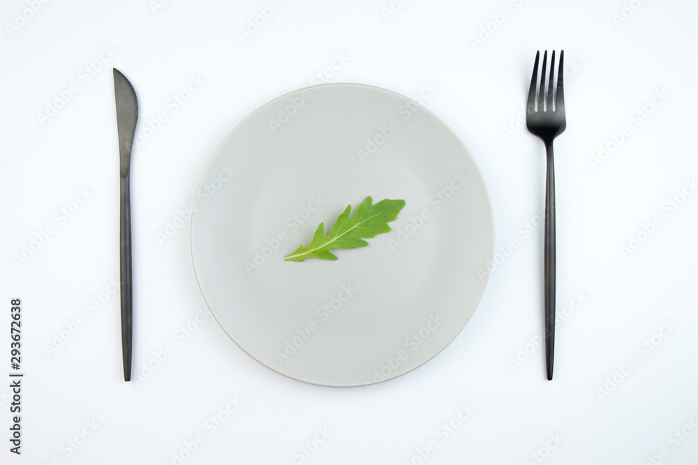Arugula leaves on a gray plate. The concept of proper and dietary nutrition. Arugula leaves on a gray plate. The concept of proper and dietary nutrition.