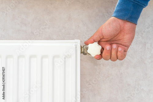 Hand adjusting the knob of heating radiator.