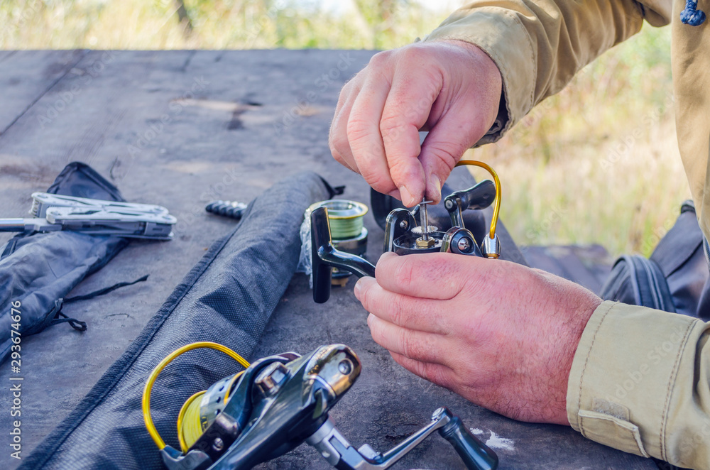 Fototapeta premium a man repairs a fishing reel with improvised means