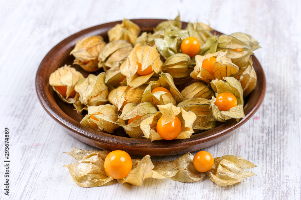 Physalis on a clay dish. Ripe berries of autumn physalis fruit Physalis on a clay dish. Ripe berries of autumn physalis fruit