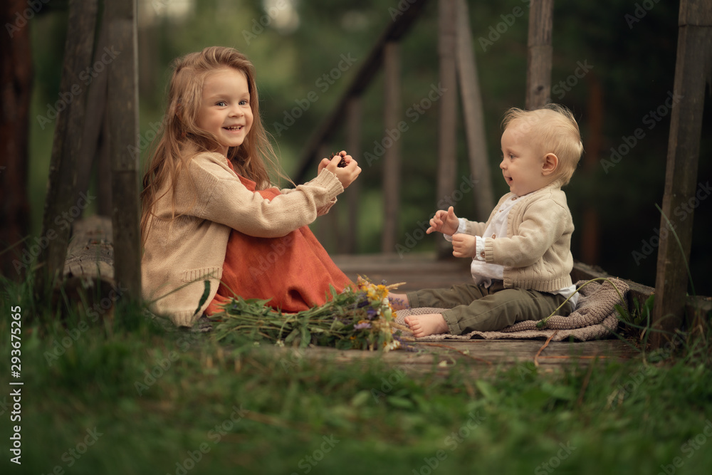 brother and sister sitting on the wooden bridge and playing together