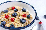 Oatmeal with fresh blueberries and red currant berries. Diet food - oatmeal porridge in a plate with a spoon.