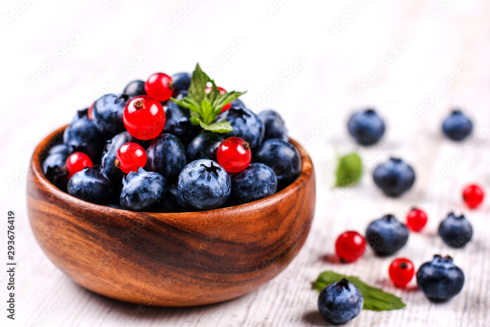 Fresh blueberries and red currants with mint leaves in a wooden bowl on burlap. Diet food, vegan berries Fresh blueberries and red currants with mint leaves in a wooden bowl on burlap. Diet food, vegan berries