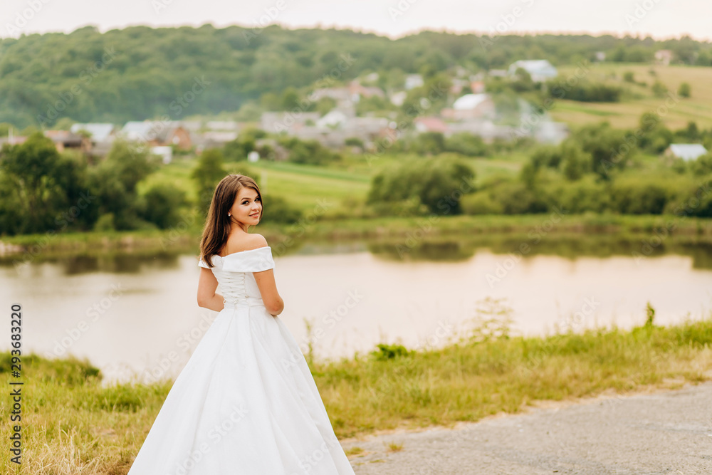 Beautiful bride in white dress posing in the park