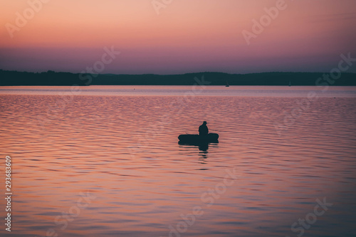 Wallpaper Mural silhouette of fishermen alone in a boat swimming on a lake. sunset background. Torontodigital.ca