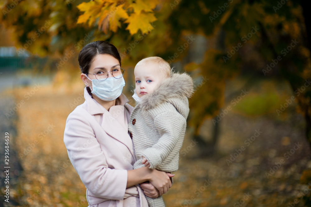 mom in a medical face mask holds a little daughter in her arms. mom in a medical face mask holds a little daughter in her arms.