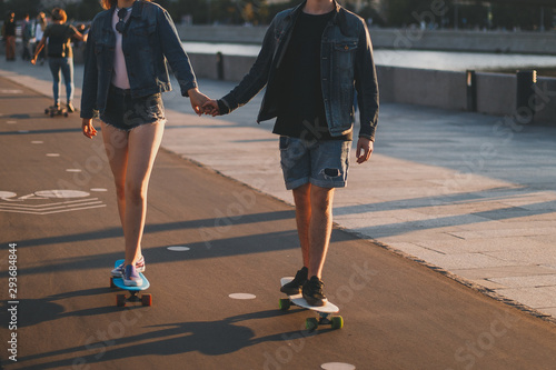 couple in love riding skateboards around the city at sunset, face not visible 1
