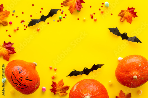 Halloween background with pumpkins and decorative bats on yellow table top view frame space for text