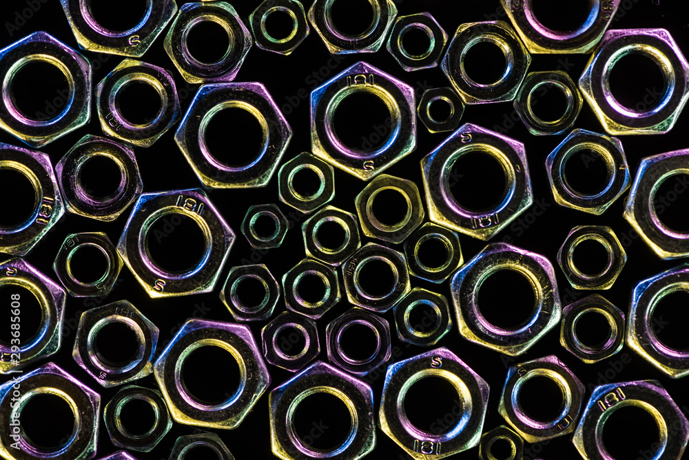 close up view of scattered diverse metal nuts isolated on black