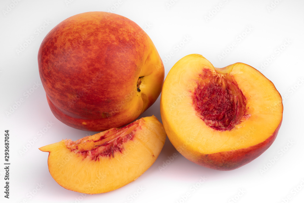two ripe nectarines, one whole, the other in pieces highlighted on a white background close-up two ripe nectarines, one whole, the other in pieces highlighted on a white background close-up
