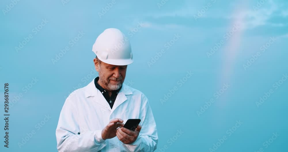 Portrait of happy engineer browsing fun content on smartphone smiling wearing working suit staying outdoor under blue sky. Portrait of happy engineer browsing fun content on smartphone smiling wearing working suit staying outdoor under blue sky.