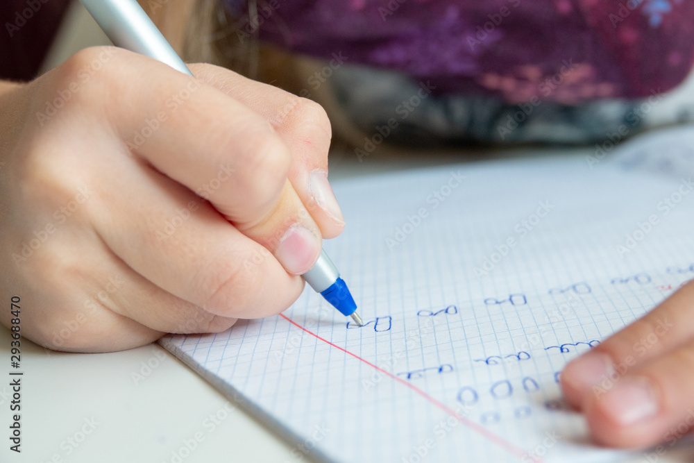 Kid holding pen and writing in notebook. Close up Kid holding pen and writing in notebook. Close up