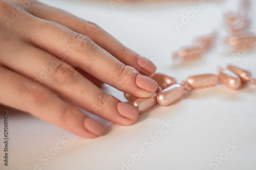 Natural beige nails  with beige capsules on  white desk. Care natural concept