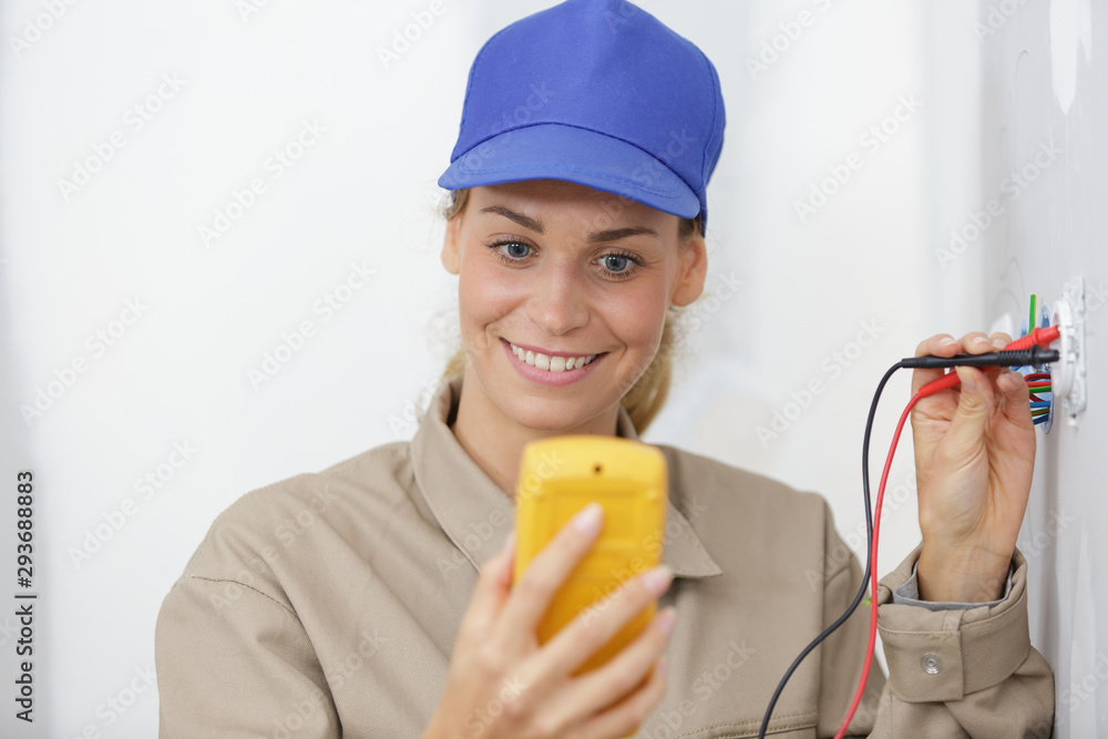 happy female electrician testing a wall socket happy female electrician testing a wall socket