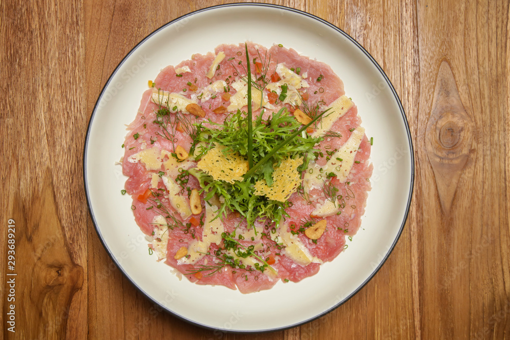 Tuna carpaccio with Italian herb dressing served on the wooden table. Exquisite dish. Creative restaurant meal concept. Tuna carpaccio with Italian herb dressing served on the wooden table. Exquisite dish. Creative restaurant meal concept.