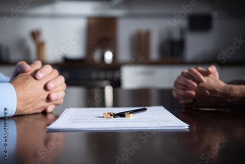 Foto partial view of couple sitting at table with clenched hands near divorce documen
