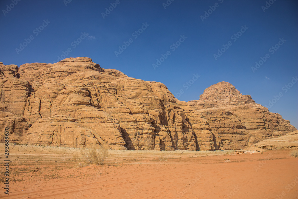 planet Earth world heritage touristic destination site Wadi Rum Jordan Middle East scenery landscape view sand valley foreground and picturesque mountain ridge on blue sky background 