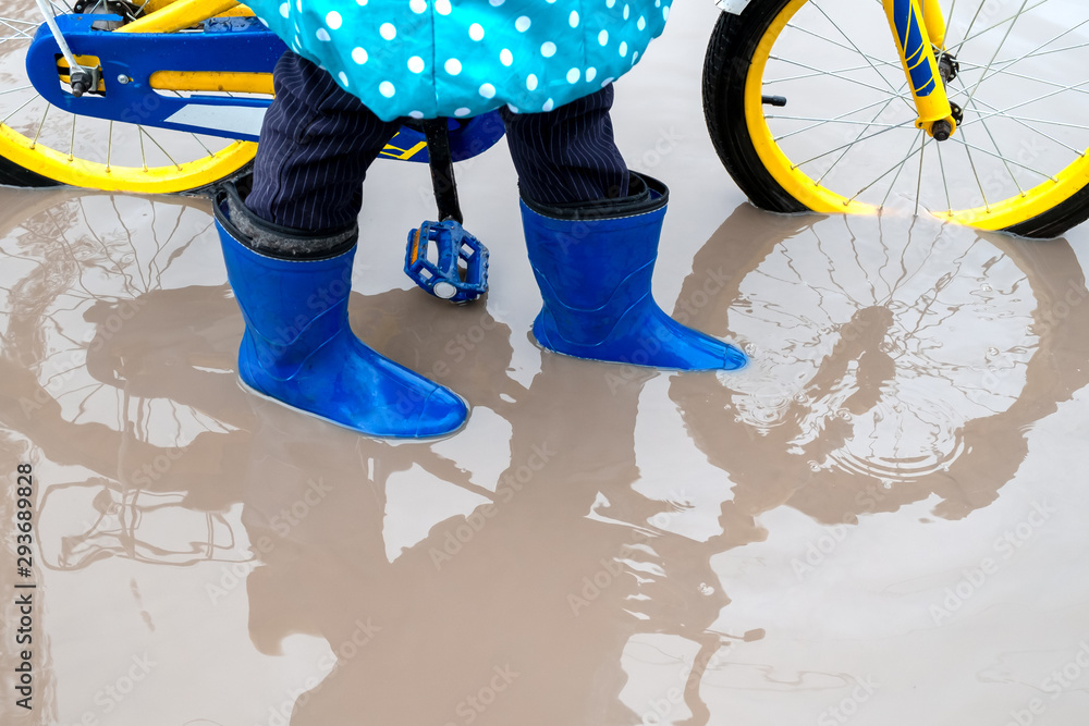 child in blue rubber boots is worth in dirty a puddle of. girl holding ...