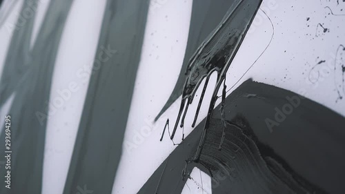 black paint drips down the canvas. the artist draws. slow motion.