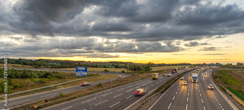 Colourful sunset at M1 motorway near Flitwick junction with blurry cars in United Kingdom