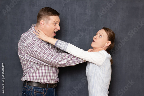 Foto Enraged man and woman are strangling each other by throat
