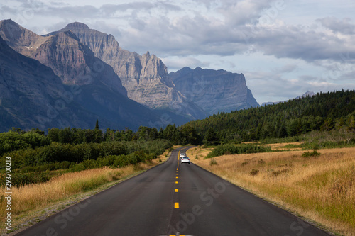 Beautiful View of Scenic Highway with American Rocky Mountain Landscape in the background during a Cloudy Summer Morning. Taken in Glacier National Park, Montana, United States.