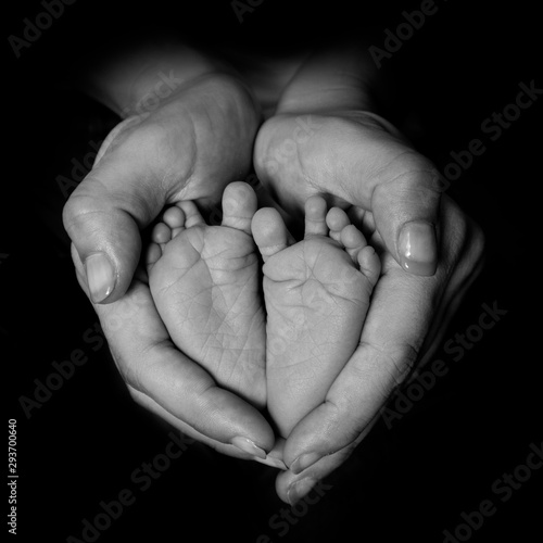 Madre envolviendo con sus manos los pies de su hijo recién nacido