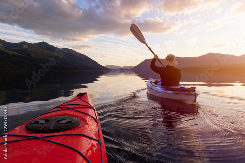 Adventurous Man Kayaking in Lake McDonald during a sunny summer sunset with American Rocky Mountains in the background. Taken in Glacier National Park, Montana, USA. photo