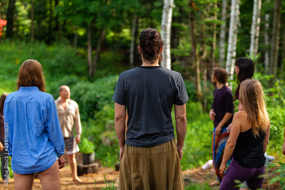 Diverse people enjoy spiritual gathering A multigenerational group of individuals are seen standing in a circle in a forest clearing as they practice shamanic and native traditions in nature. Diverse people enjoy spiritual gathering A multigenerational group of individuals are seen standing in a circle in a forest clearing as they practice shamanic and native traditions in nature.