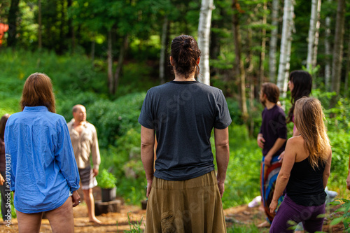 Diverse people enjoy spiritual gathering A multigenerational group of individuals are seen standing in a circle in a forest clearing as they practice shamanic and native traditions in nature.