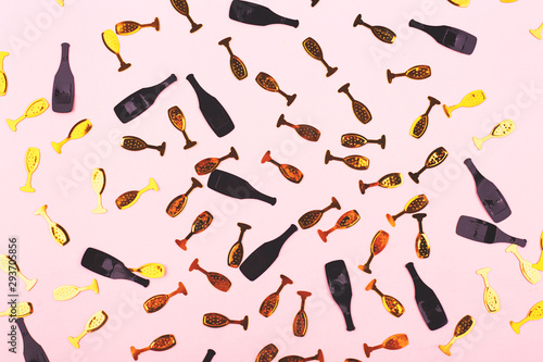 Champagne bottles and glasses confetti on pink background.