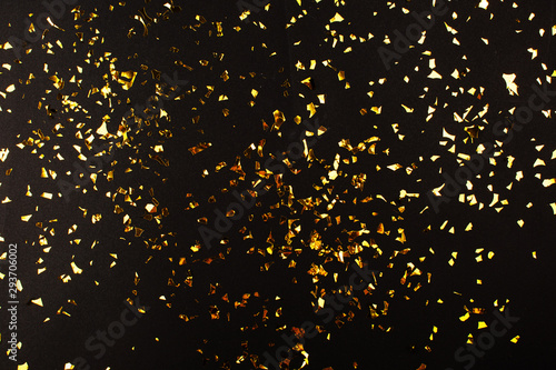 Foto Gold foil confetti on black background. Flatlay.