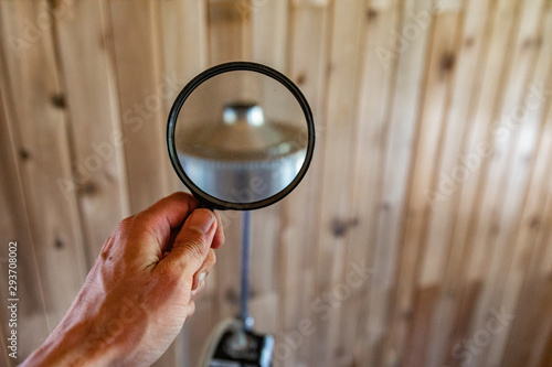 Indoor damp & air quality (IAQ) testing. A first person perspective of a man holding a magnifying glass towards an impactor on an aluminum tripod during a residential home inspection, with copy-space. photo