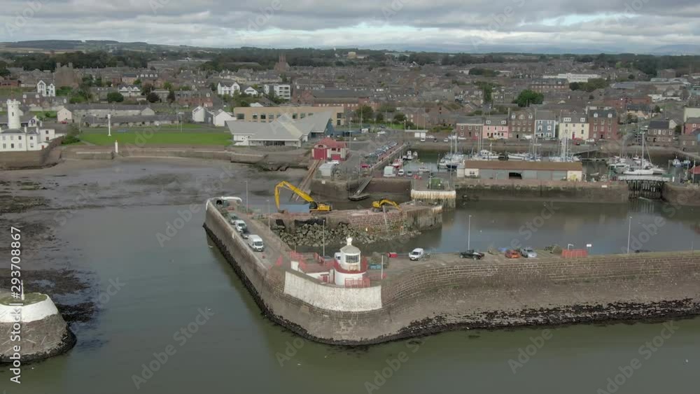 An aerial view of Arbroath harbour and town on a cloudy day. Left to right circling view of the harbour with the town in the background. An aerial view of Arbroath harbour and town on a cloudy day. Left to right circling view of the harbour with the town in the background.
