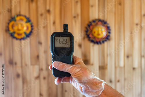 Indoor damp & air quality (IAQ) testing. A close up view of a home environmental quality inspector using a handheld air quality monitor with digital display showing a moderate level of pollutants. photo