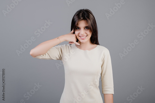 Wallpaper Mural beautiful brunette woman showing call me gesture imitating phone isolated over grey Torontodigital.ca