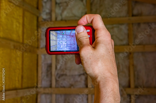 Indoor damp & air quality (IAQ) testing. Home inspector photographing timber frame building cavity walls filled with fiberglass insulation during an in depth inspection, in first person perspective. photo