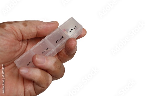 Pill organizer with pills in hand or palm of a patient or elderly isolated on white background. Close-up.