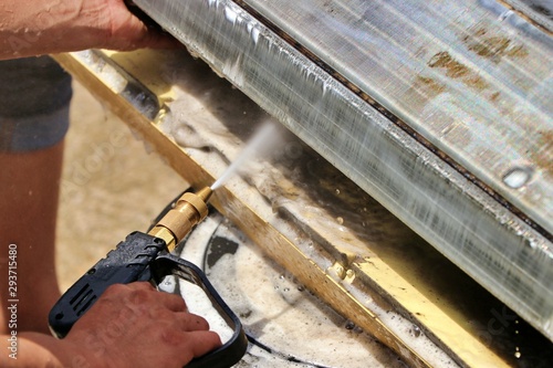 Wash away foam from air conditioner with high pressure water sprayer. Air conditioner maintenance, repair & service concept.